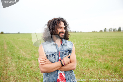 Image of smiling young hippie man on green field