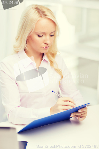 Image of smiling businesswoman with clipboard in office