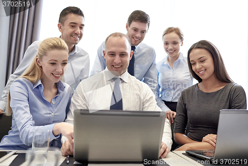 Image of smiling business people with laptop in office