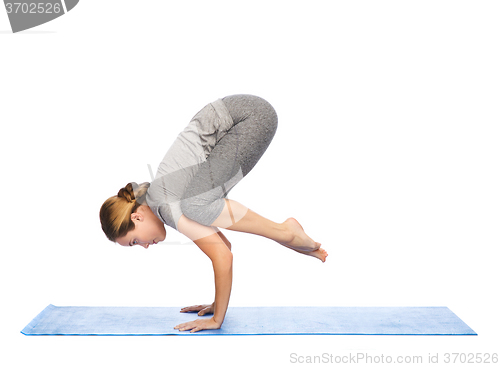 Image of woman making yoga in crane pose on mat