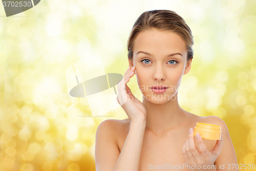 Image of young woman appying cream to her face