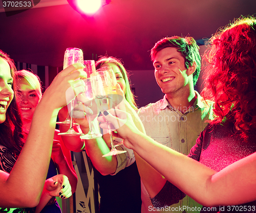 Image of smiling friends with glasses of champagne in club