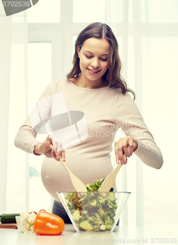 Image of happy pregnant woman preparing food at home