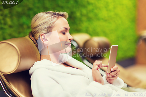 Image of beautiful young woman with smartphone at spa