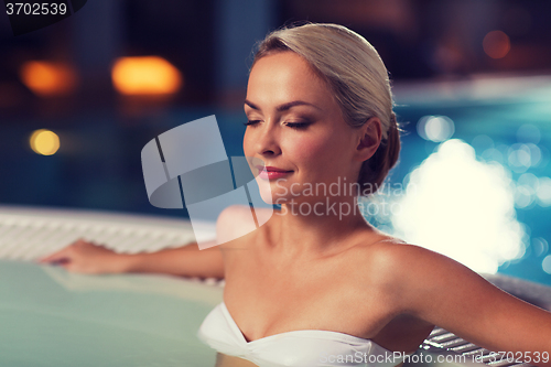 Image of happy womani sitting in jacuzzi at poolside