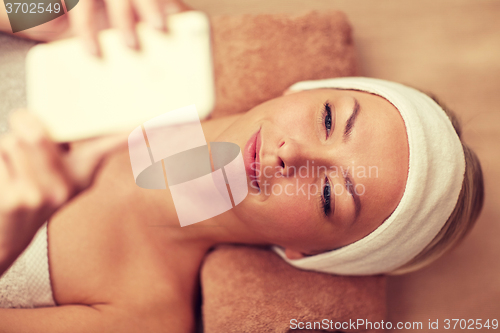 Image of close up of smiling woman with smartphone in spa