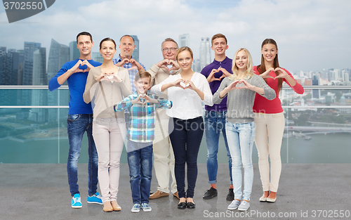 Image of people showing heart hand sign over city waterside