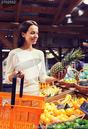 Image of happy young woman with food basket in market