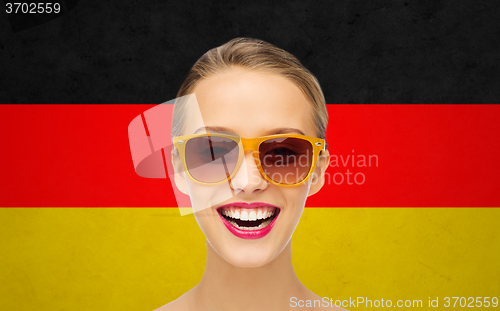 Image of happy young woman in sunglasses over german flag