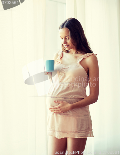 Image of happy pregnant woman with cup drinking tea at home