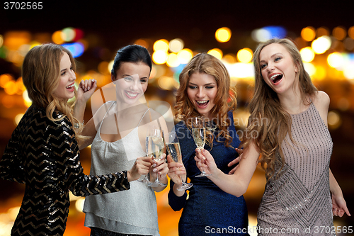 Image of happy women clinking champagne glasses over lights