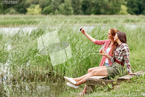 Image of happy women taking selfie by smartphone outdoors