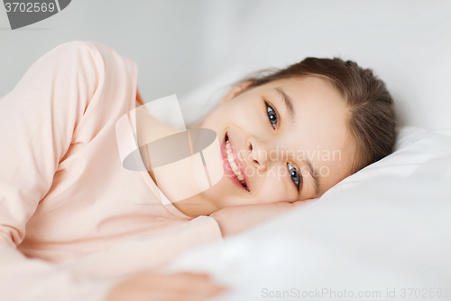 Image of happy smiling girl lying awake in bed at home