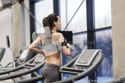 Image of woman with earphones exercising on treadmill
