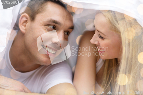 Image of happy couple under blanket in bed