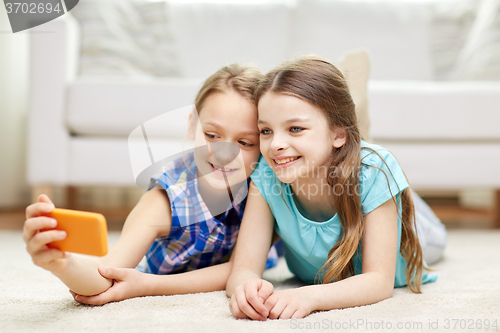 Image of happy girls with smartphone taking selfie at home