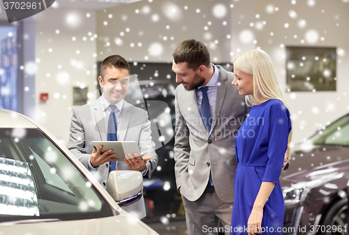 Image of happy couple with car dealer in auto show or salon