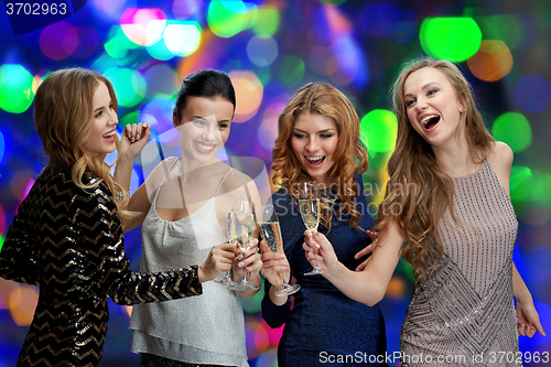 Image of happy women clinking champagne glasses over lights