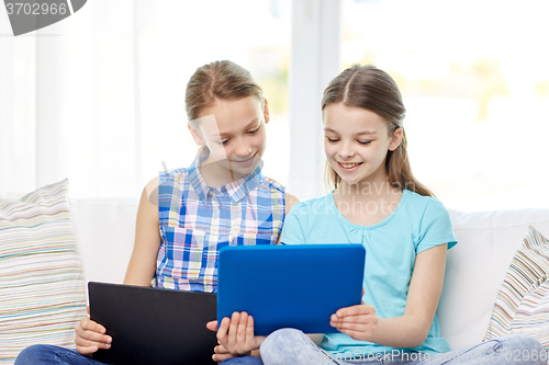 Image of happy girls with tablet pc sitting on sofa at home