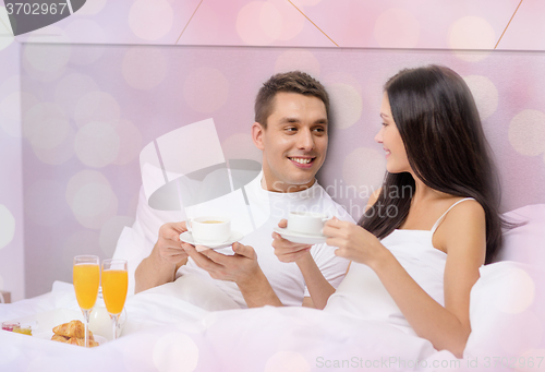 Image of happy couple having breakfast in bed at hotel