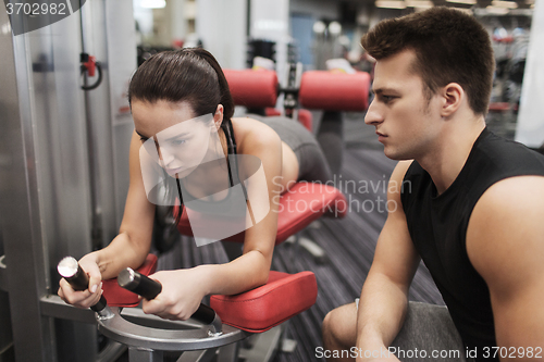 Image of young woman with trainer exercising on gym machine