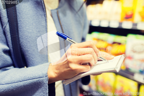 Image of close up of woman writing to notepad in market