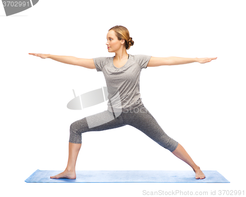 Image of woman making yoga warrior pose on mat