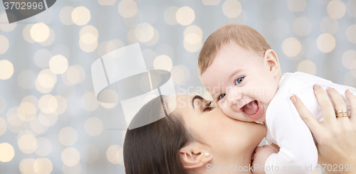 Image of happy mother kissing her baby over lights