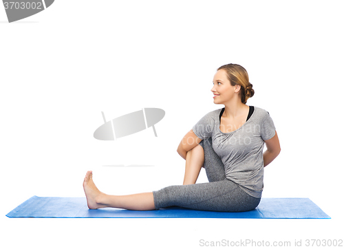 Image of woman making yoga in twist pose on mat