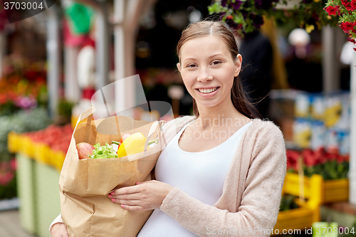 Image of pregnant woman with bag of food at street market