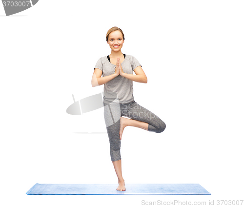 Image of woman making yoga in tree pose on mat