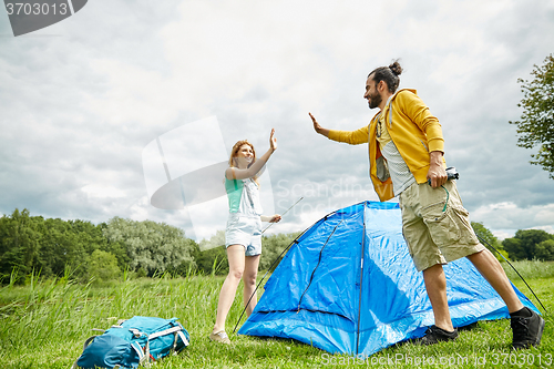 Image of happy couple setting up tent outdoors