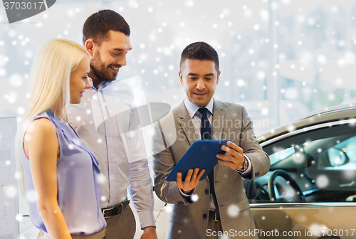 Image of happy couple with car dealer in auto show or salon