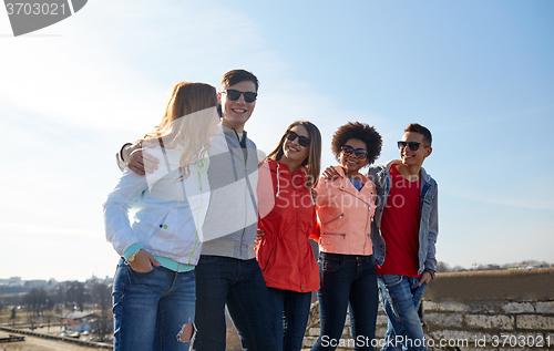 Image of happy teenage friends walking along city street