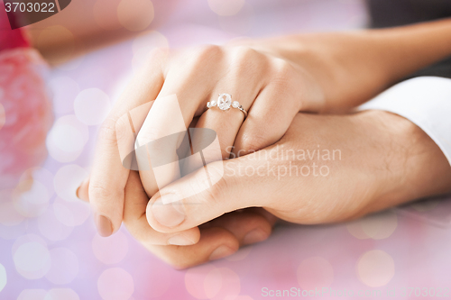 Image of close up of couple hands with engagement ring