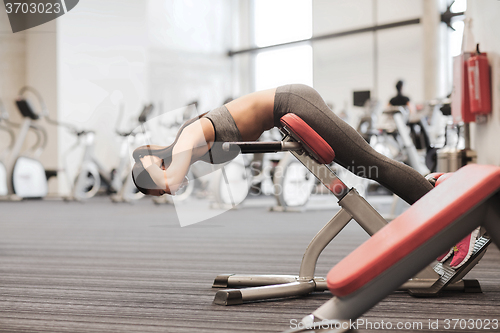 Image of young woman flexing back muscles on bench in gym