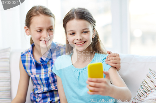 Image of happy girls with smartphone taking selfie at home