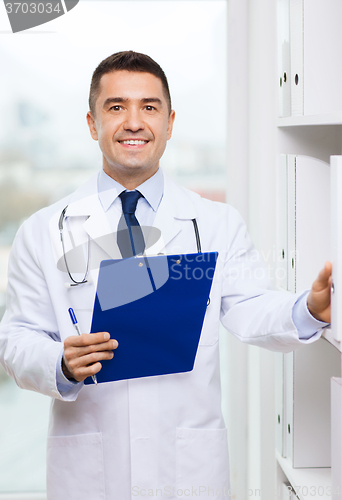 Image of happy doctor with clipboard in medical office