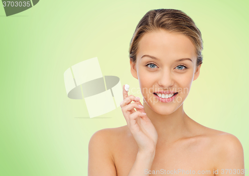 Image of happy young woman applying cream to her face