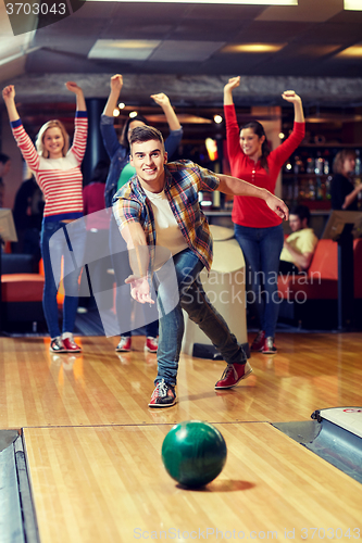 Image of happy young man throwing ball in bowling club