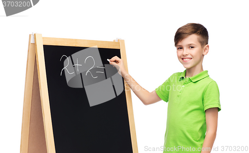 Image of happy boy solving math on school blackboard