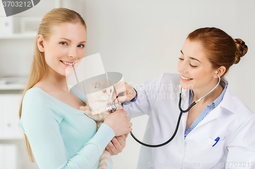 Image of happy woman with cat and doctor at vet clinic