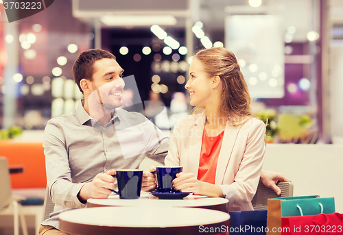 Image of happy couple with shopping bags drinking coffee