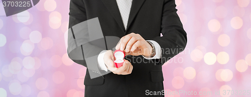 Image of close up of man with gift box and engagement ring