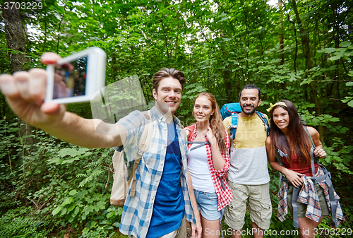 Image of friends with backpack taking selfie by smartphone