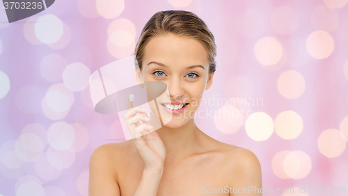 Image of happy young woman applying cream to her face