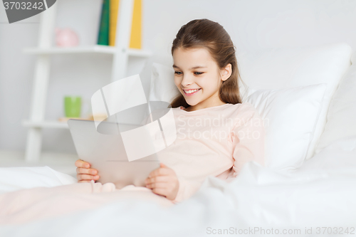 Image of happy girl lying in bed with tablet pc at home