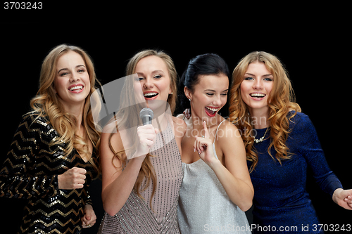 Image of happy young women with microphone singing karaoke