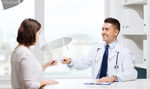 Image of smiling doctor giving pills to woman at hospital