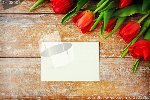 Image of close up of red tulips and blank paper or letter